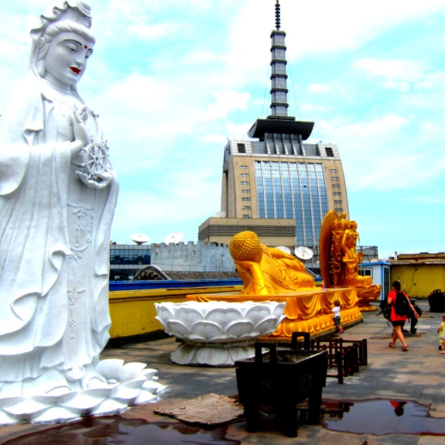 Large Buddha statues contrasted with t.v. building